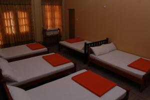 una stanza con quattro letti con cuscini rossi di Anura Guest Inn a Ella