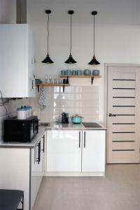cocina blanca con armarios blancos y microondas en Romantic Apartment on Rynok square with Air-Conditioning, en Leópolis