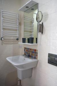 ein weißes Waschbecken im Bad mit Spiegel in der Unterkunft Romantic Apartment on Rynok square with Air-Conditioning in Lwiw