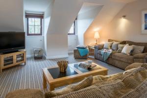 a living room with a couch and a tv at Sunnyside Cottage in Crantock