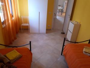 a room with two beds and a hallway with a refrigerator at La Casa Dei Colori in Zafferana Etnea