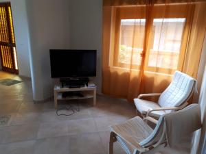 een woonkamer met een televisie en 2 stoelen bij La Casa Dei Colori in Zafferana Etnea