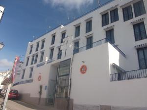 a white building with a balcony on the side of it at Apartahotel Playa Conil in Conil de la Frontera