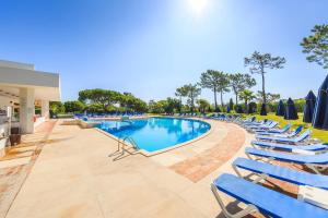 a swimming pool with lounge chairs and umbrellas at Victory Village 9F in Quinta do Lago