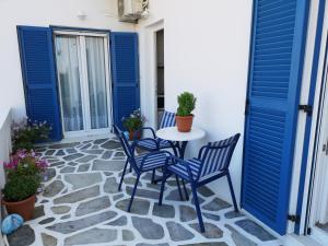 een patio met blauwe deuren en stoelen en een tafel bij Minas House Antiparos in Antiparos Stad