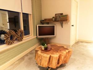 een woonkamer met een boomstronk salontafel en een televisie bij The Old Garage in Tilburg