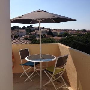 a table and chairs with an umbrella on a balcony at Studio Hesperides in Balaruc-les-Bains