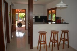 a kitchen with three bar stools and a counter at Casa do Sol in Paracuru