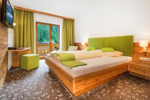 a bedroom with a large bed with green accents at Hotel Oberwirt - Das herzliche Hotel in Viehhofen