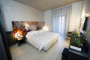 a bedroom with a white bed and a painting on the wall at Arli Hotel Business and Wellness in Bergamo