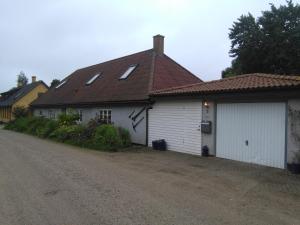 a white house with a brown roof and a driveway at Langøhuset in Langebæk