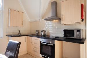a kitchen with a stove and a microwave at Ormes Hey Apartments in Llandudno
