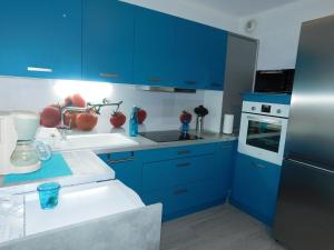 una cocina azul con armarios azules y fregadero en Le petit nid en Lourdes