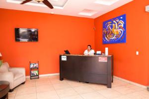 a woman sitting at a counter in an orange room at Hotel El Viejo Inn in Chinandega