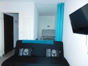 um quarto com uma cama preta e uma televisão de ecrã plano em Le petit nid em Lourdes