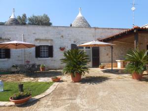 un patio con sombrillas y plantas frente a un edificio en B&B La Collina Degli Ulivi, en Fasano