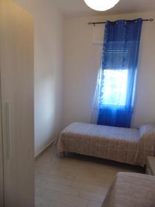 a bedroom with a bed and a window with blue curtains at Appartamento il Geranio in Quercianella
