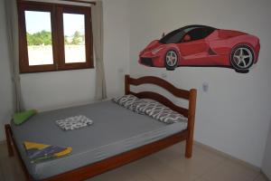 a bedroom with a bed with a red car on the wall at Casa do Sol in Paracuru