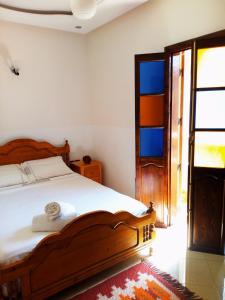 een slaapkamer met een bed met een houten bedframe bij Casa Mogador in Essaouira