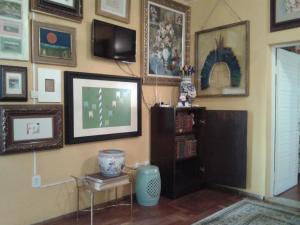 a living room with a tv and paintings on the wall at Mini Hostel Fine Art in Vitória da Conquista