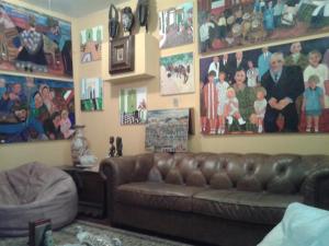ein Wohnzimmer mit einem braunen Sofa und Bildern an der Wand in der Unterkunft Mini Hostel Fine Art in Vitória da Conquista