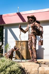 a statue of a man in a costume standing next to a fire hydrant at Jolly Swagman Acccommodation Park in Toowoomba