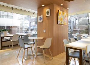 uma sala de jantar com mesas, cadeiras e janelas em Ueno First City Hotel em Tóquio