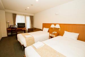una camera d'albergo con 2 letti e una scrivania di Hotel Yokohama Camelot Japan a Yokohama