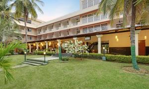 an exterior view of a hotel with palm trees at Royal Orchid Resort & Convention Centre, Yelahanka Bangalore in Bangalore