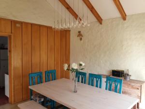 a dining room table with blue chairs and a vase with flowers at Casa en Pingueral in Dichato