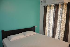 a bed in a room with a blue wall and curtains at Moonlight Residency in Tiruchirappalli
