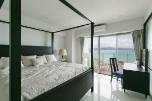 宇流麻Hideout Okinawa Uruma的一间卧室，配有一张床、一张书桌和一扇窗户