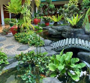 a garden with a pond and a bench and plants at Peti Mas Hotel Malioboro in Yogyakarta