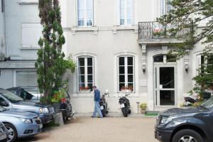 un hombre parado fuera de una casa blanca en Hotel Montsegur, en Carcassonne