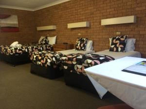 una camera d'albergo con tre letti e un muro di mattoni di James Street Motor Inn a Toowoomba