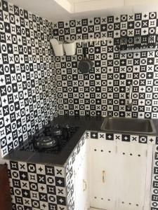 a kitchen with a black and white tiled wall at Rumah Baraka in Yogyakarta +10 photos