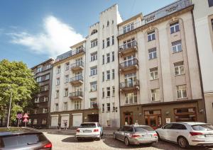 een groot gebouw met auto's ervoor geparkeerd bij Bearsleys Archers Apartments in Rīga