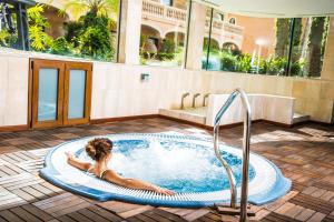 Mon Port Hotel & Spa في بويرتو دي أندراتكس: امرأة مستلقية في حوض استحمام ساخن في مبنى