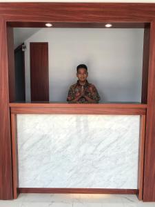 un hombre está parado detrás de una gran pared blanca en Cemerlang Inn, en Palembang
