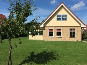 uma casa com um jardim verde com uma árvore em Vakantiehuis Zeeduinenbos em Schoorl