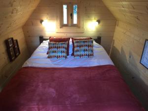 Cama en una cabaña de madera con sábanas y almohadas rojas en Cabane Aligoté en Saint-Albain