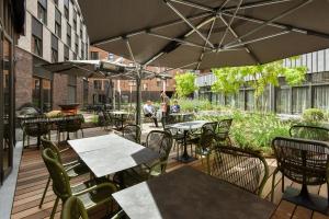 un patio al aire libre con mesas, sillas y sombrillas en Martin's All Suites, en Louvain-la-Neuve