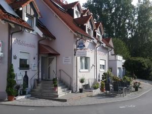 a white building with stairs and chairs on a street at Landhotel Garni am Mühlenwörth in Tauberbischofsheim