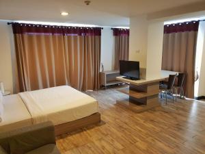 een slaapkamer met een bed en een bureau met een televisie bij Mooks Residence in Pattaya