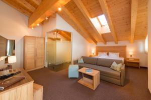 ein Wohnzimmer mit einem Sofa, einem Bett und einem Tisch in der Unterkunft Alpinhotel Monte Superior - Silvretta Card Premium Betrieb in Galtür