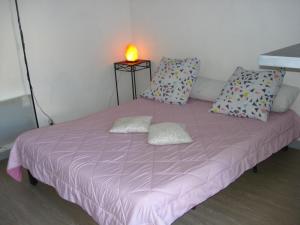 a pink bed with two pillows and a candle on it at Résidence Home 90 in Avignon