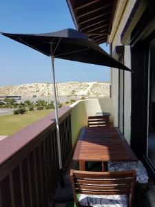 un patio con 2 mesas y una sombrilla en el balcón en Réf 542 Seignosse océan , bel appartement avec parking privatif, à 250m de la plage, 5 personnes en Seignosse