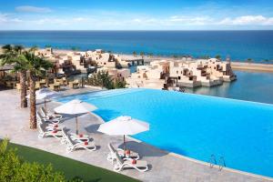 - une piscine avec chaises longues et parasols et l'océan dans l'établissement The Cove Rotana Resort - Ras Al Khaimah, à Ras al Khaimah