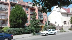 un coche blanco estacionado frente a un edificio en Baross apartman, en Kaposvár
