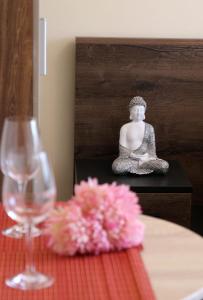 エゲルにあるOrient Apartmanházのワイングラスの横のテーブルに座る仏像